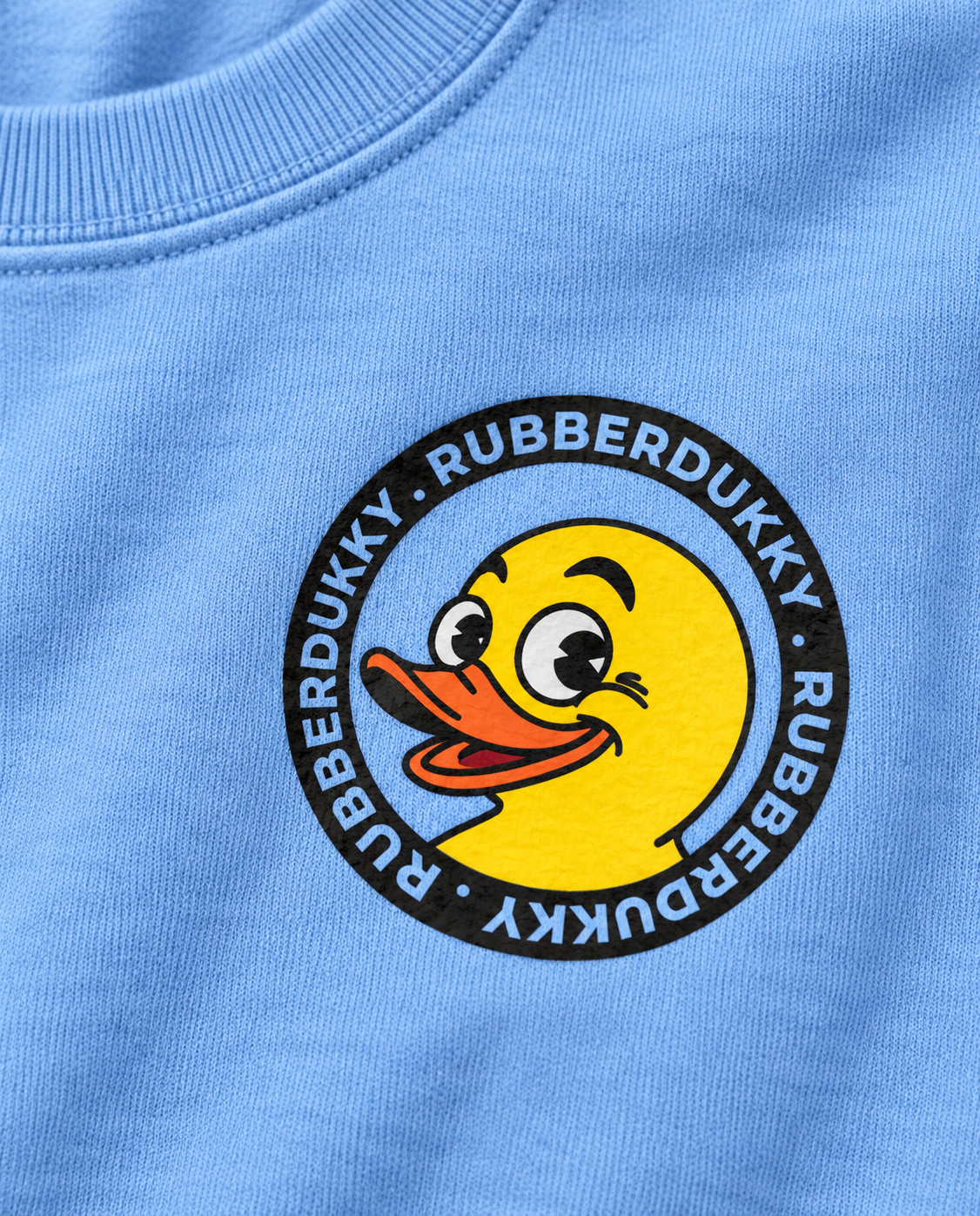 Close view of Rubberdukky duck chest emblem on blue crew sweatshirt